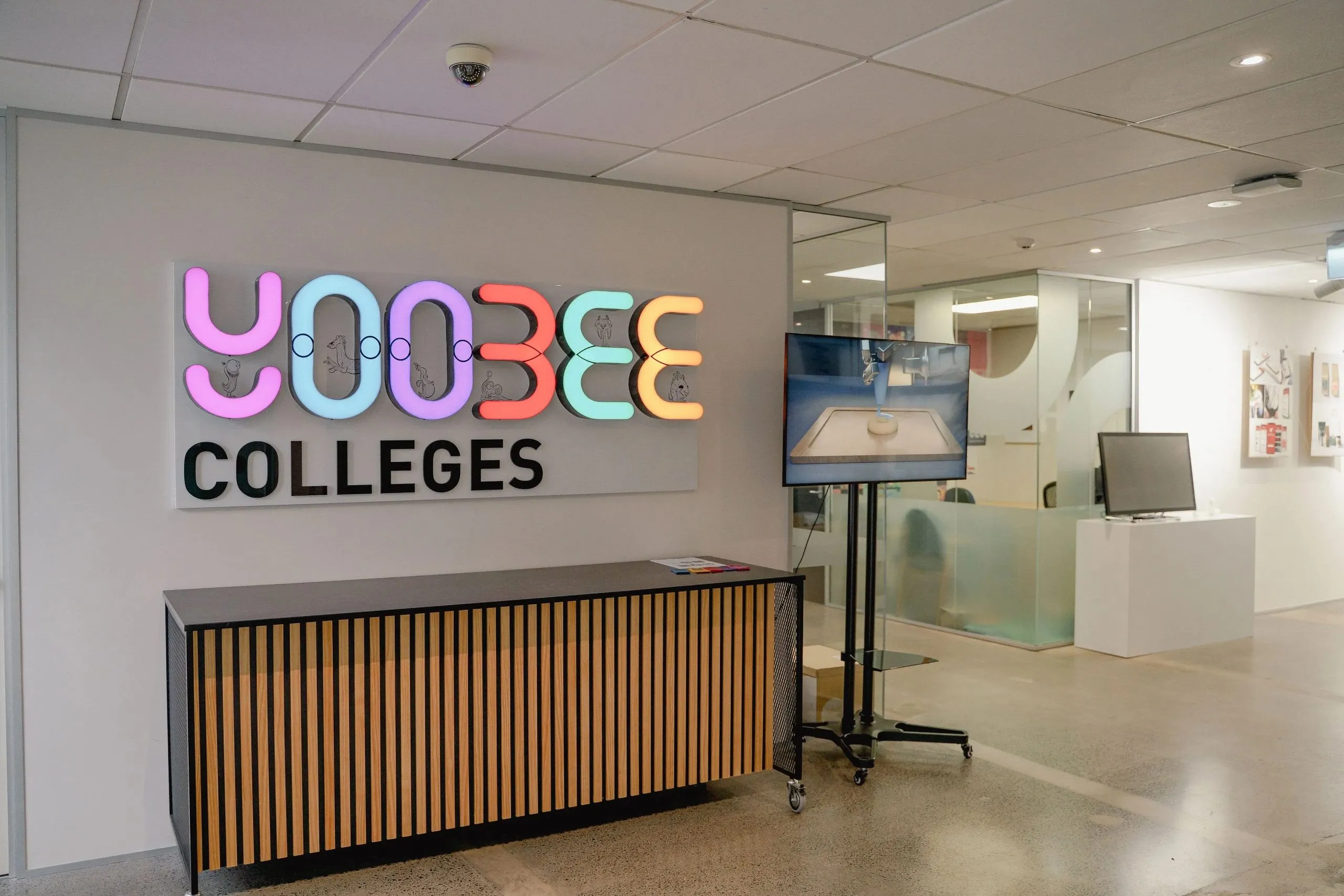 Reception desk and an illuminated Yoobee Colleges sign in the facility.