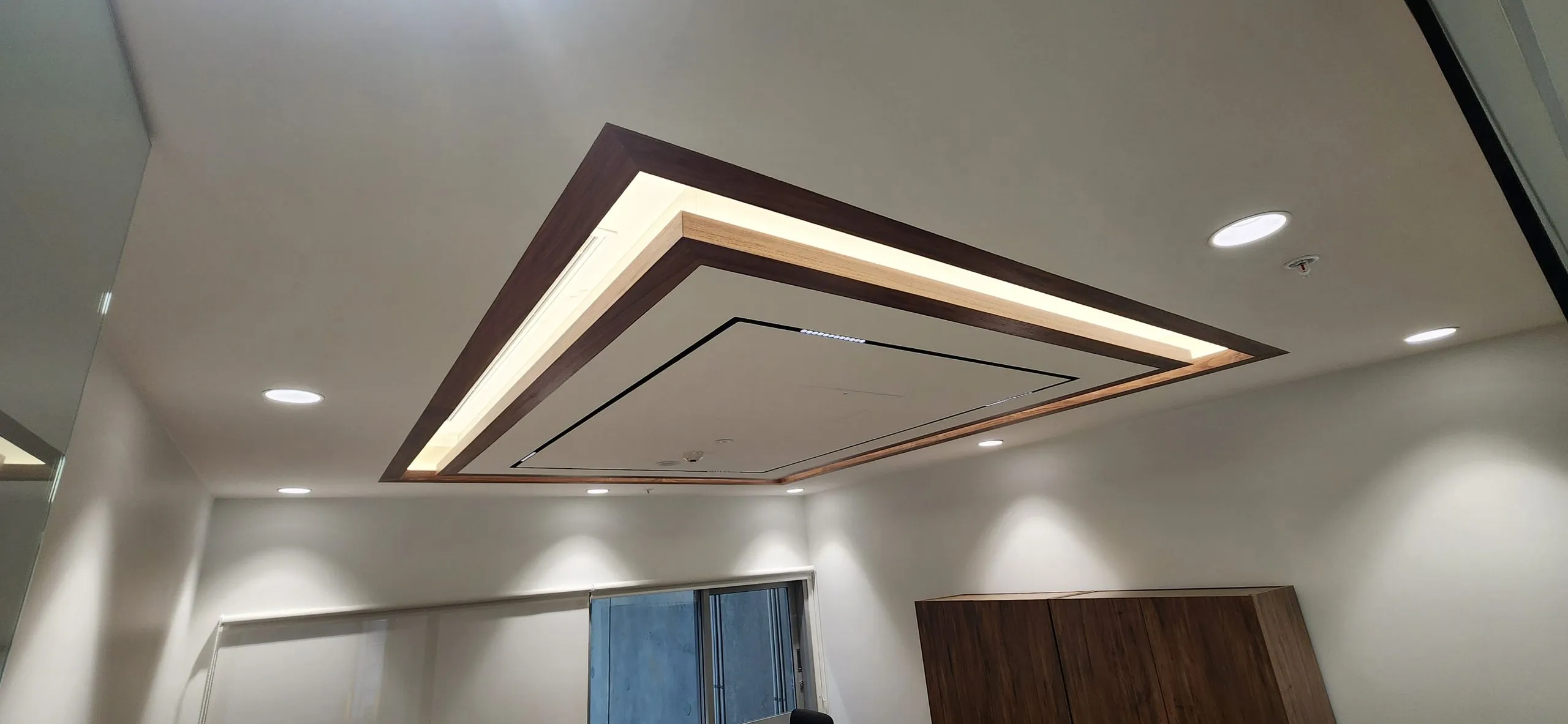 Timber-edged ceiling bulkhead and light tray above a timber cupboard.