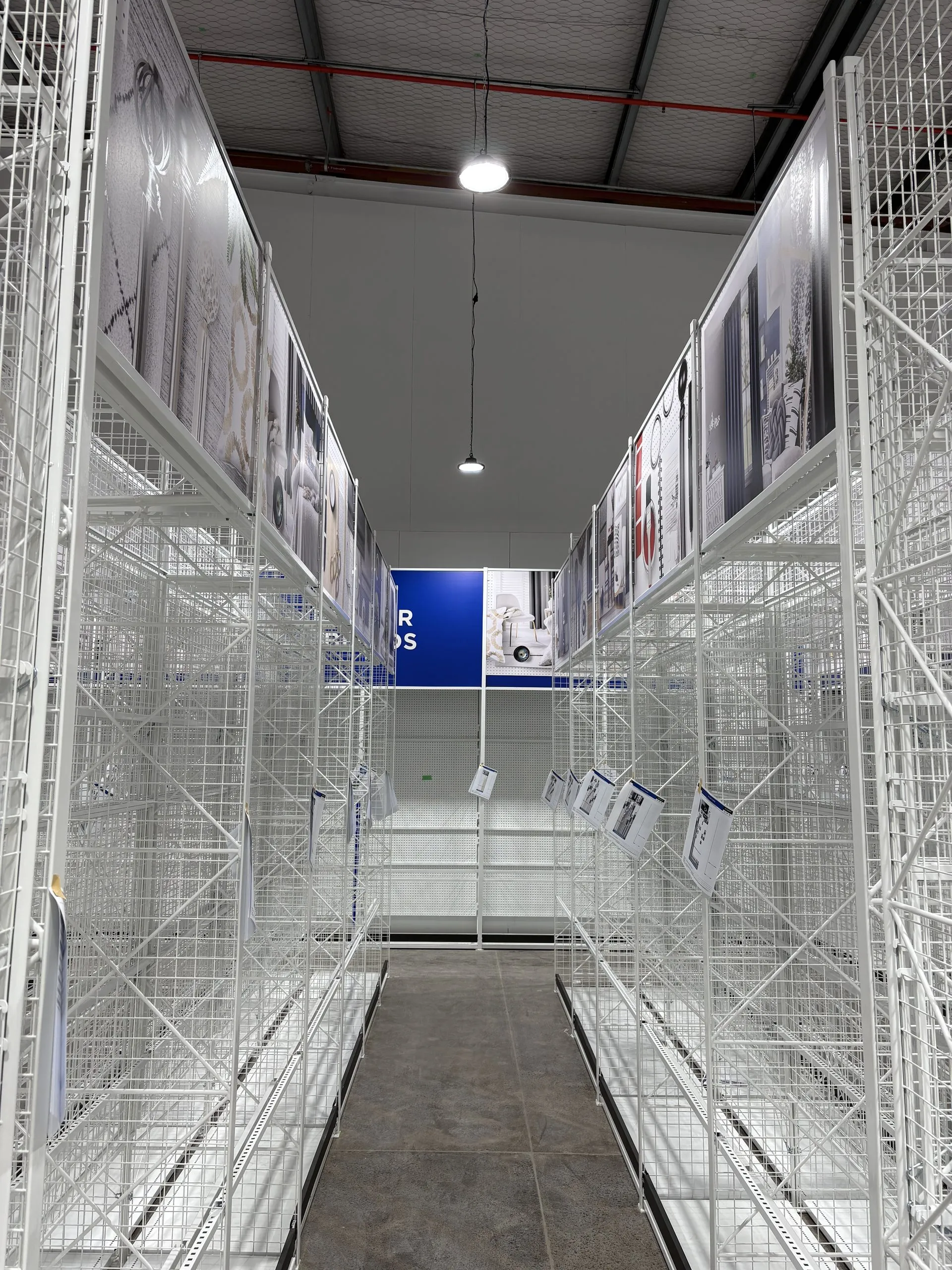 Aisle of installed white racking with category graphics, shelving and the floor left visible.