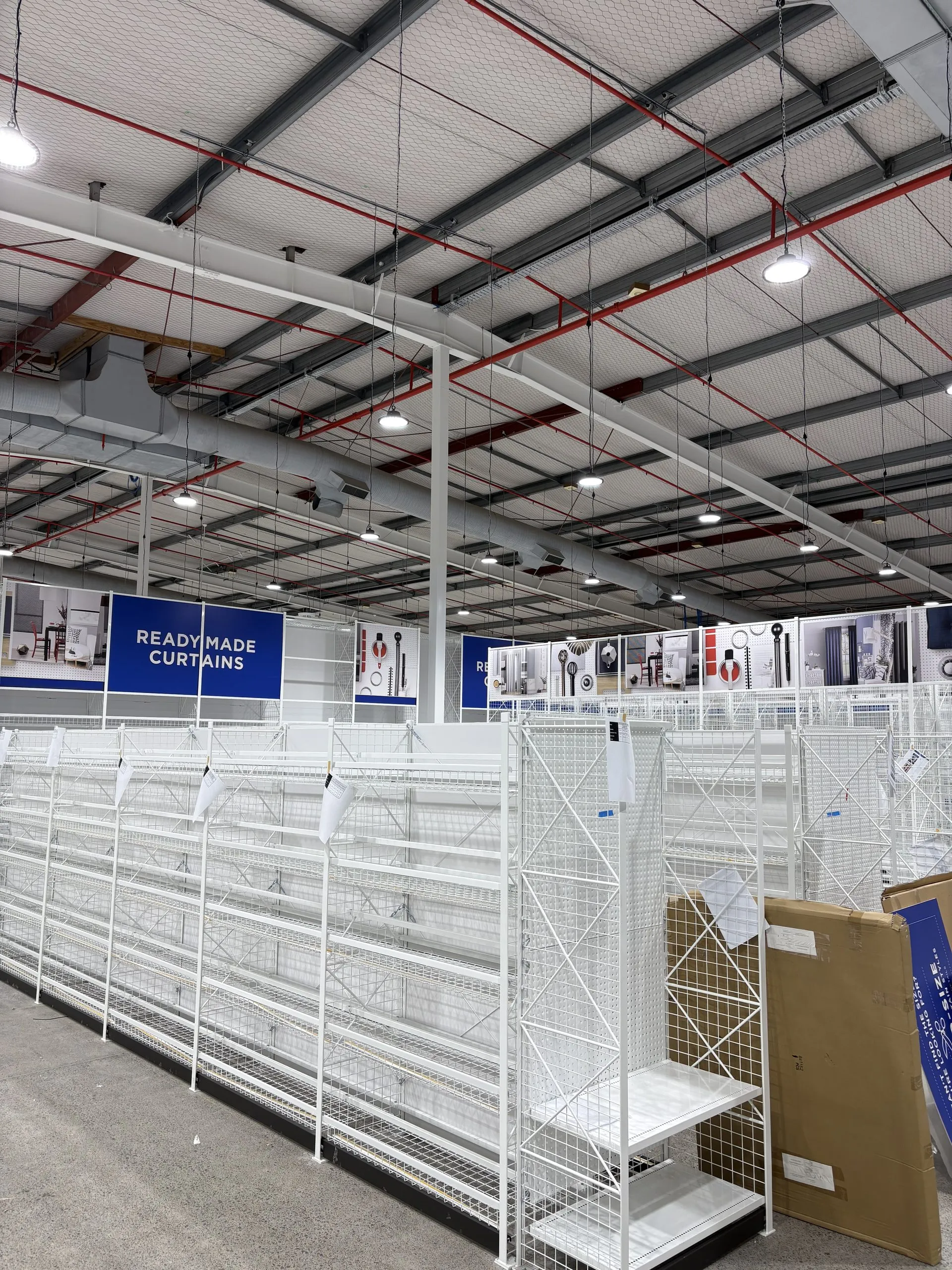 Installed white racking and Ready Made Curtains signage, with the racking and aisle kept in frame.