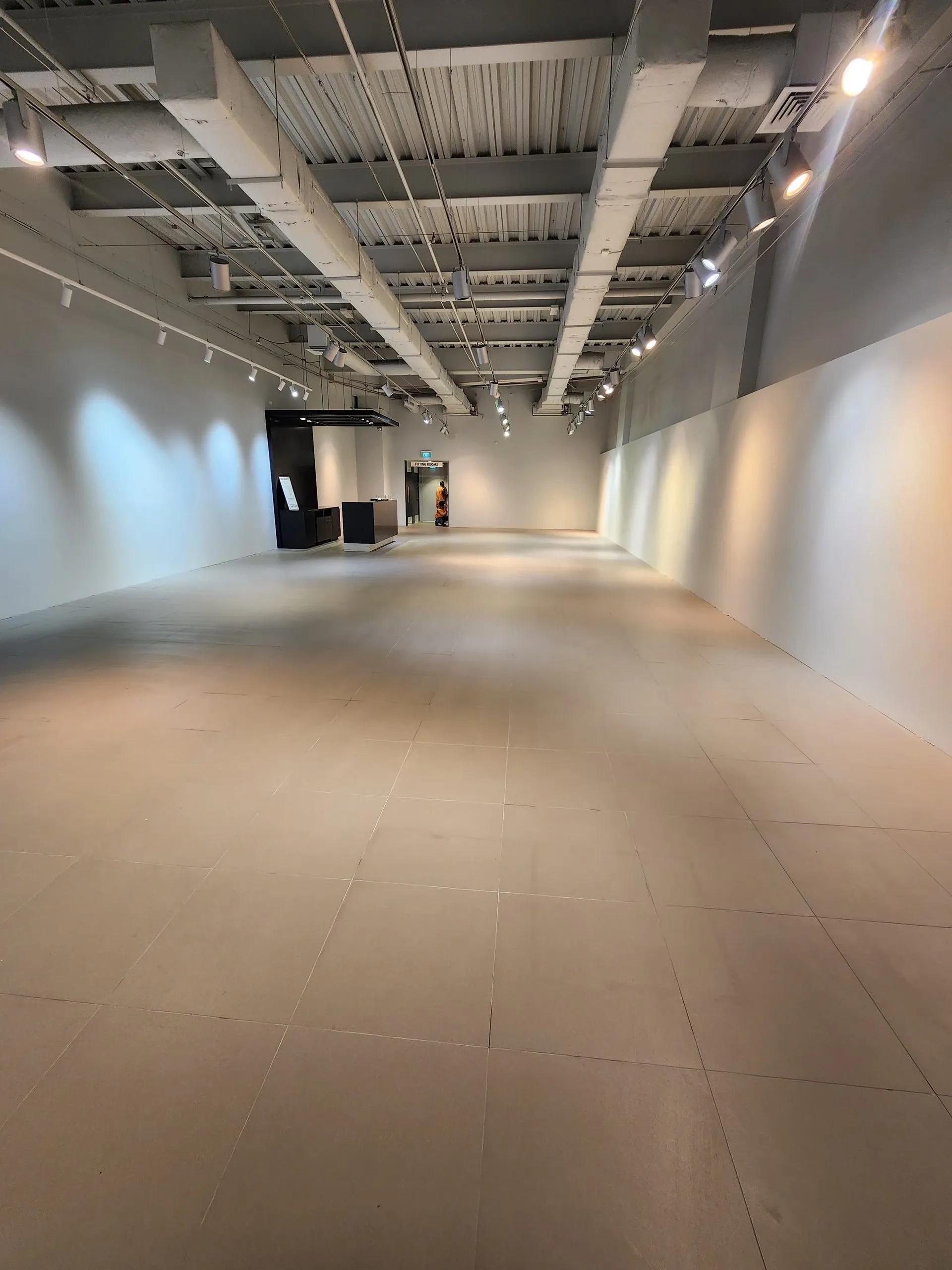 Cleared Adidas sales floor after strip-out, with the floor empty and ceiling services remaining.